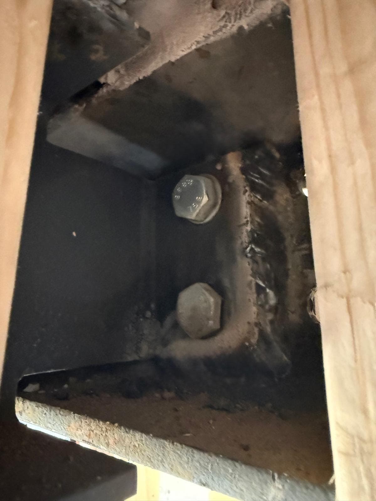 Bolted end-plate connection between two steel beams, viewed between floor joists