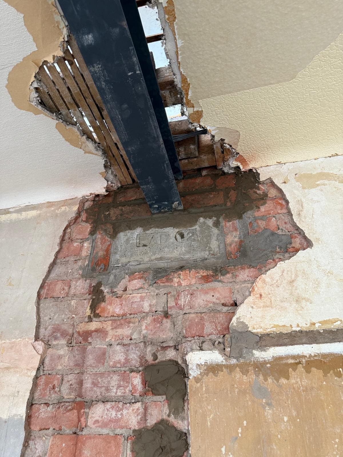 Concrete padstone under a steel beam with the brickwork rebuilt and made good below