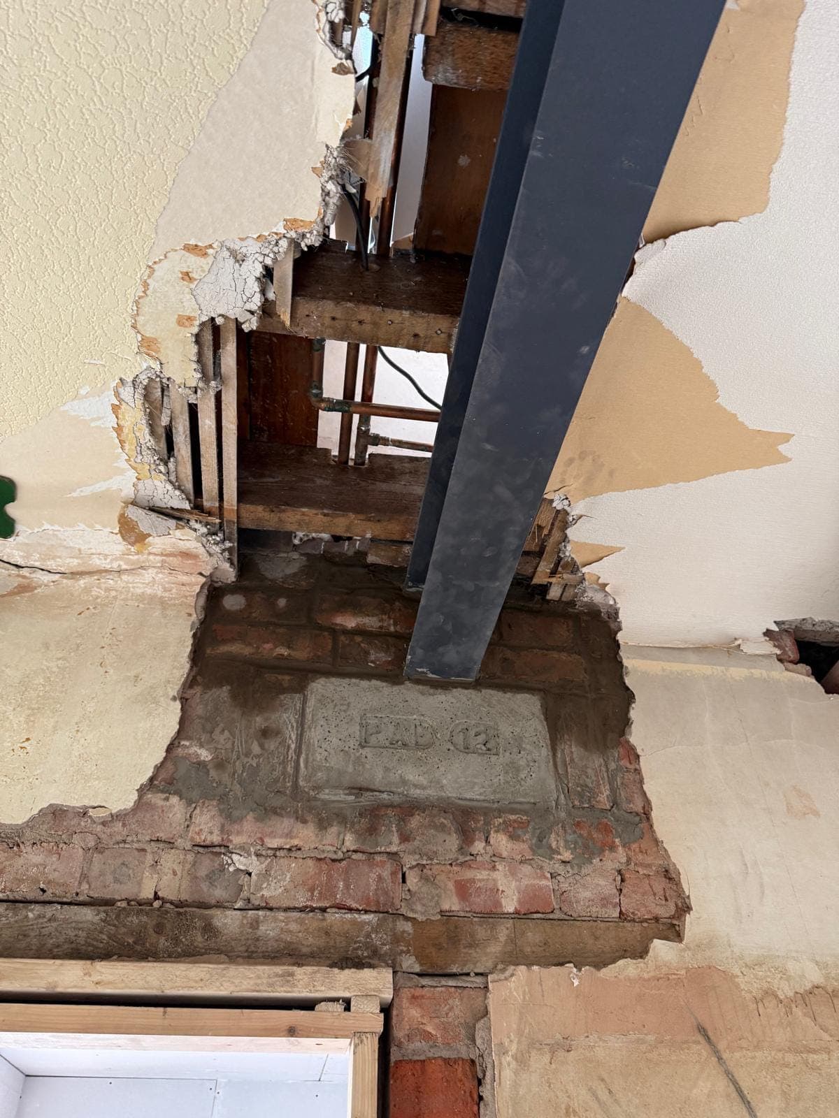 Steel beam end bearing onto a numbered concrete padstone bedded into the brickwork