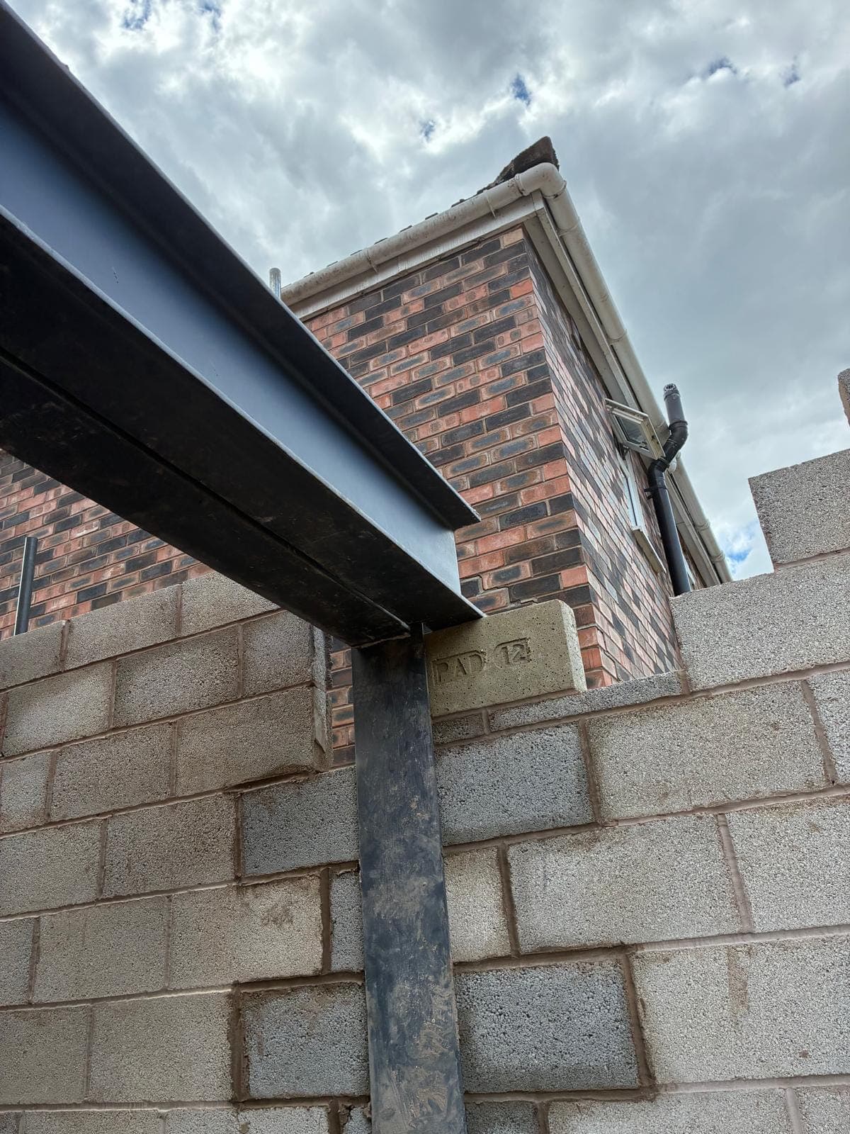 Steel beam and post on a numbered padstone bedded into new blockwork beside a house