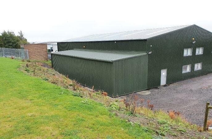 Steel-framed warehouse extension clad in green box profile to match the existing unit